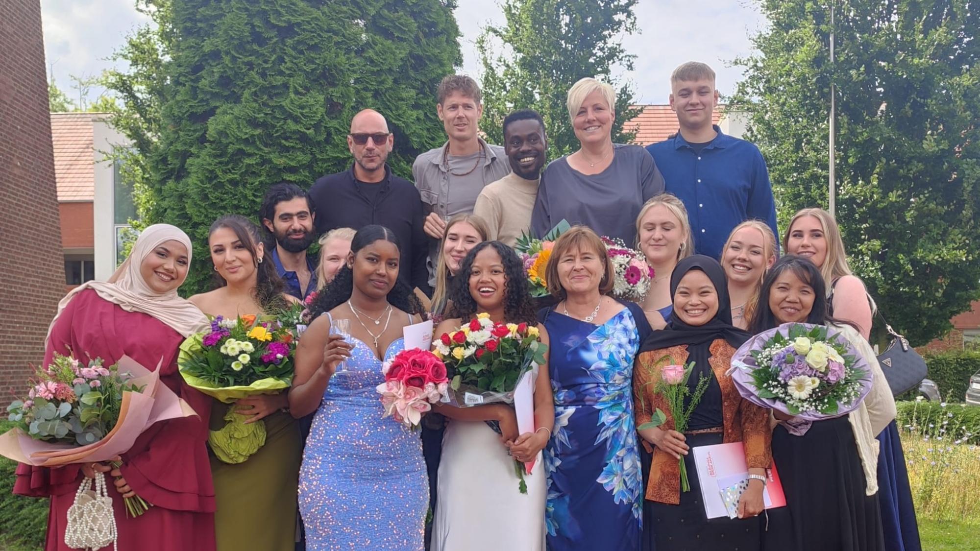 Absolventinnen und Absolventen der Ausbildung zur Pflegefachfrau beziehungsweise zum Pflegefachmann halten Blumen in den Händen und schauen in die Kamera.